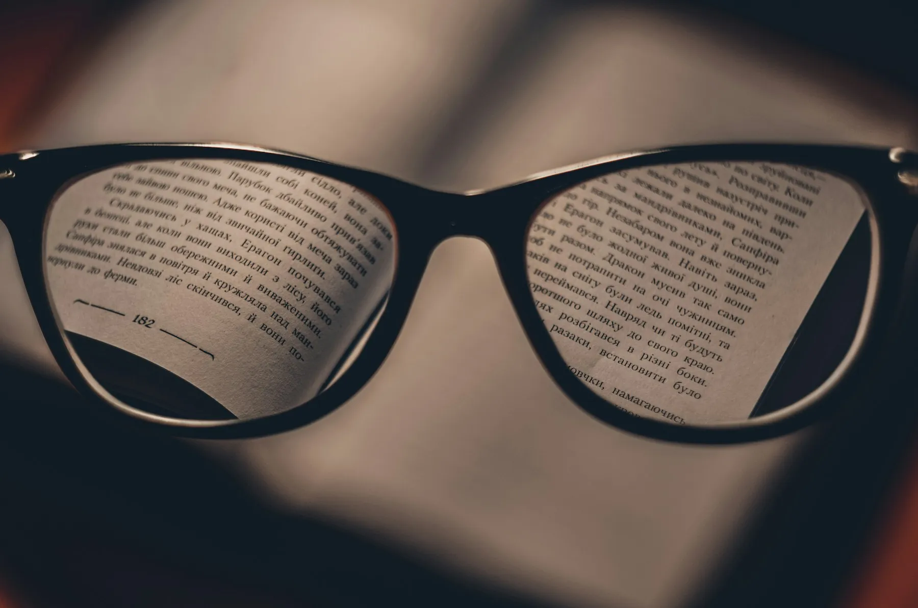 Óculos sobre as páginas de um livro, com as letras nítidas através da lente